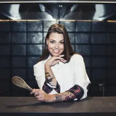 Adriana Marczewska, młoda kucharka z tatuażami, trzyma drewnianą łyżkę.