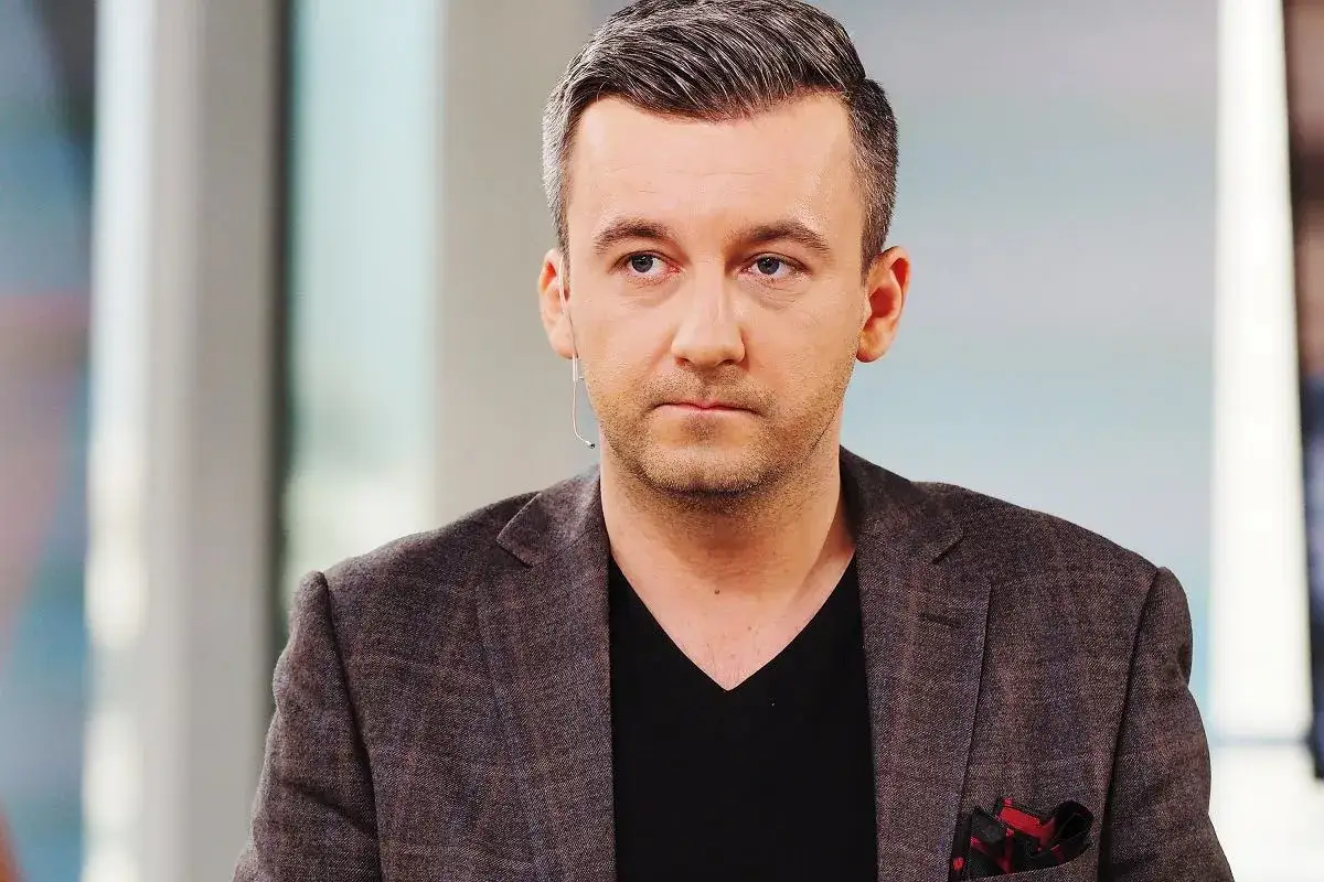Krzysztof Skórzyński, dziennikarz, w eleganckim garniturze. Ile ma lat? Trudno zgadnąć, wygląda na około 40.