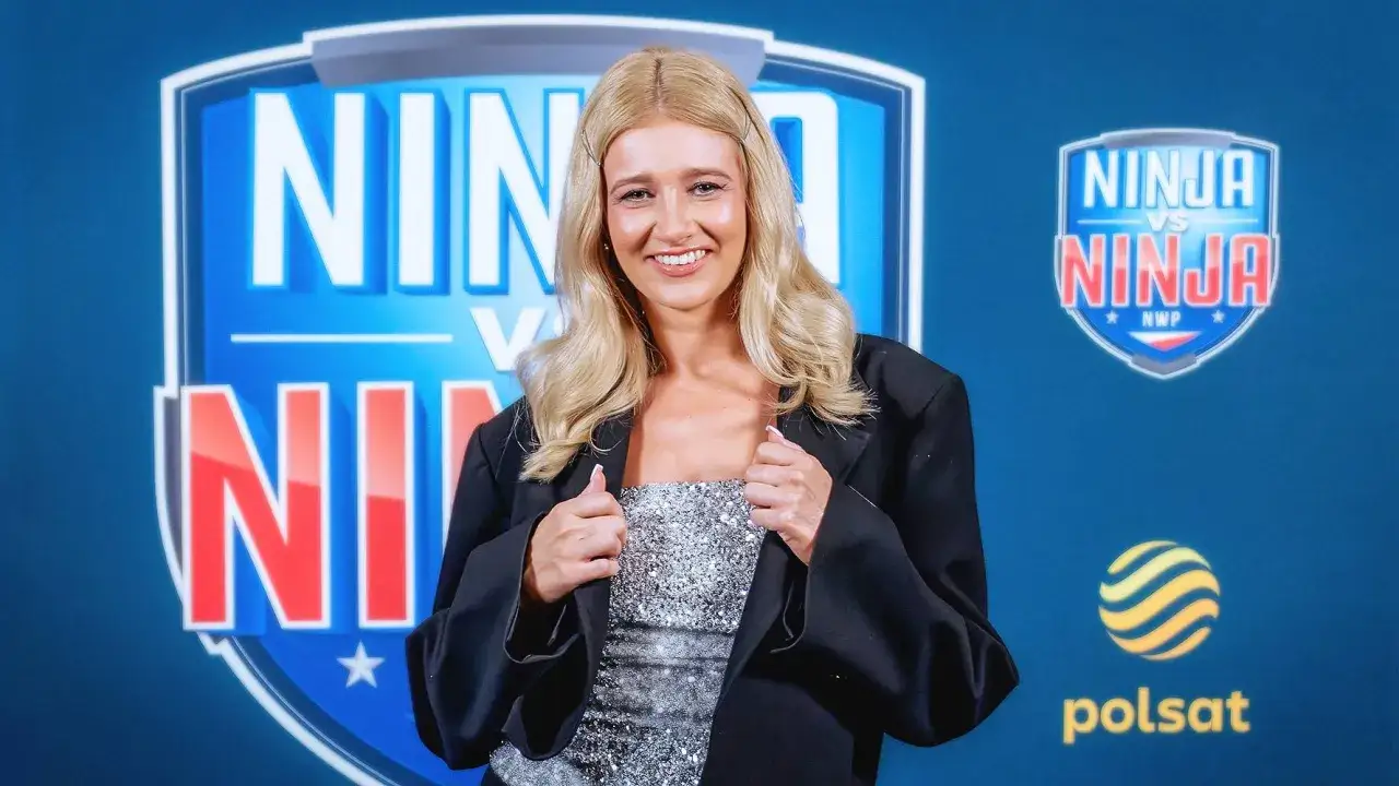 Marta Ćwiertniewicz, której wiek nie jest tu kluczowy, uśmiecha się na tle logo Ninja Warrior Polska.