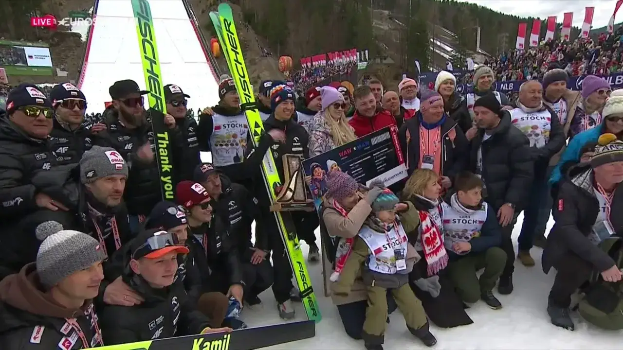 Kamil Stoch z rodziną i kibicami po skoku. Wszyscy świętują, choć w tle widać znicze, sugerujące koniec kariery Kamila Stocha.